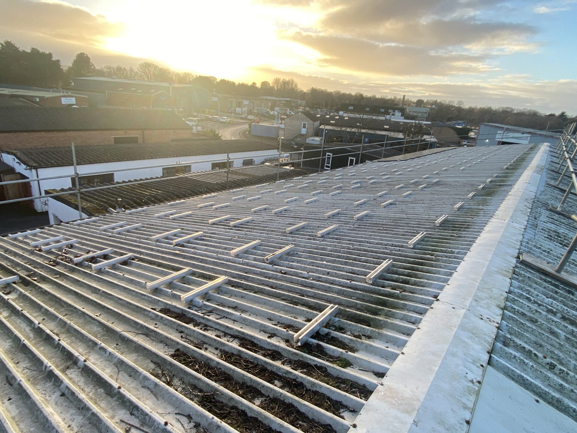 solar panel rails on roof with sun in background